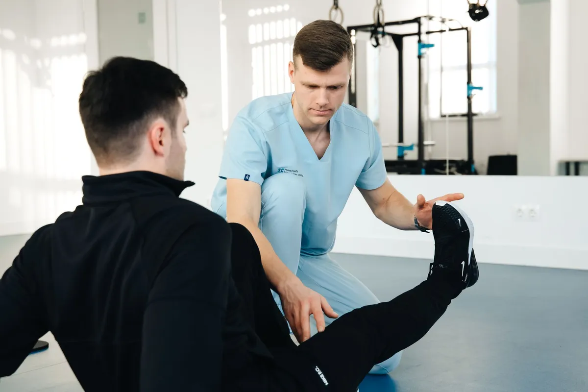 Physical therapist assisting a patient with ankle exercises on a mat