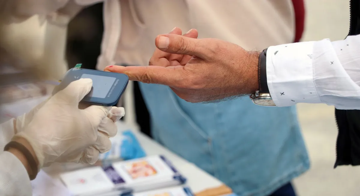 A healthcare worker checking a person’s blood sugar level at a health fair.
