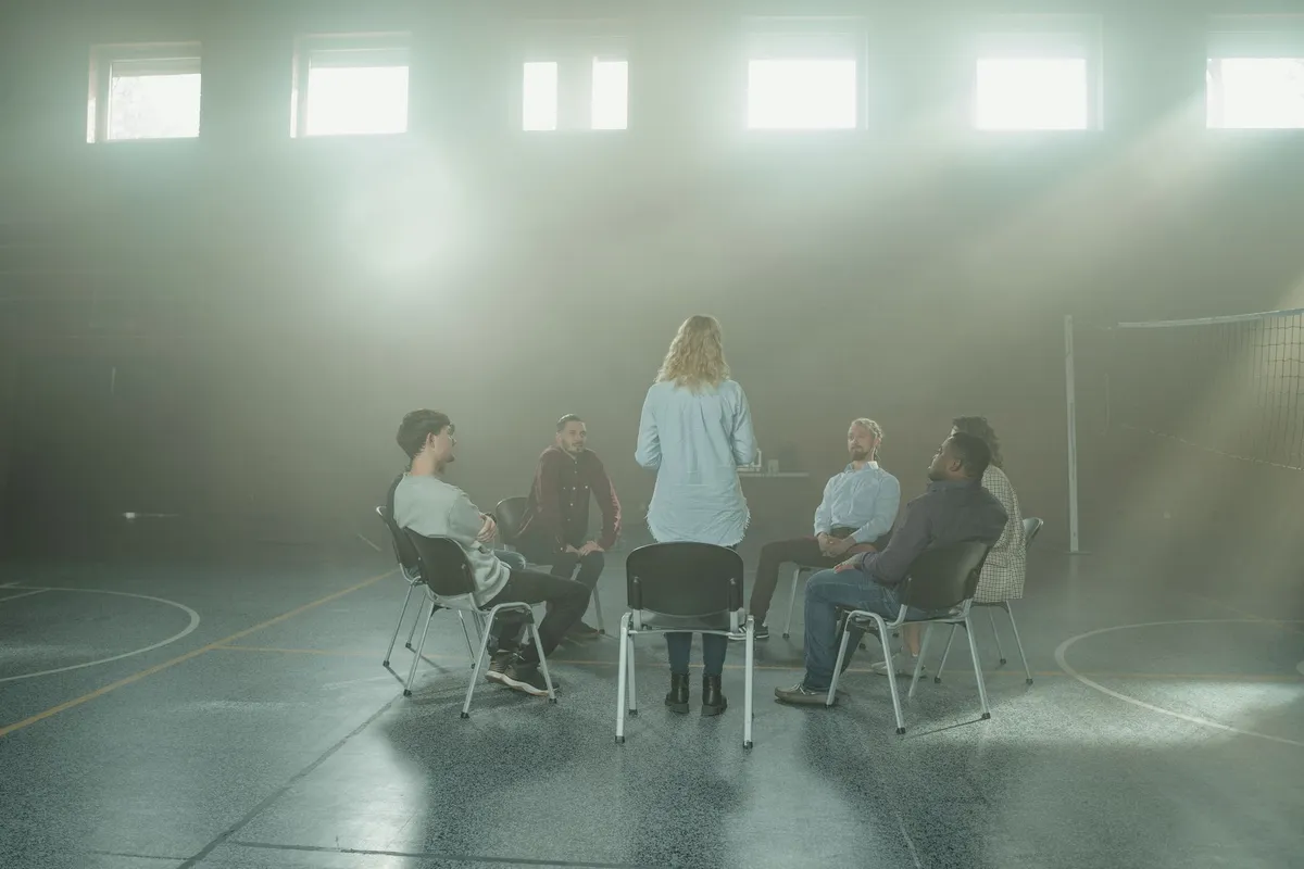Group discussion in a dimly lit gym setting, focusing on support and interaction.
