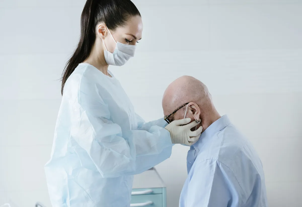 Healthcare professional examining an elderly man’s face for signs of acromegaly.