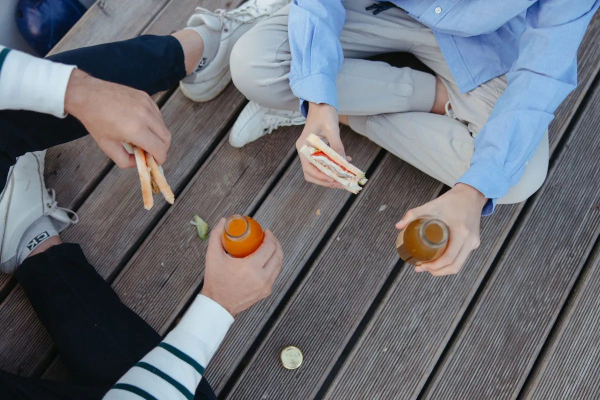 Friends enjoying snacks and drinks on a wooden surface, relevant to healthy eating.