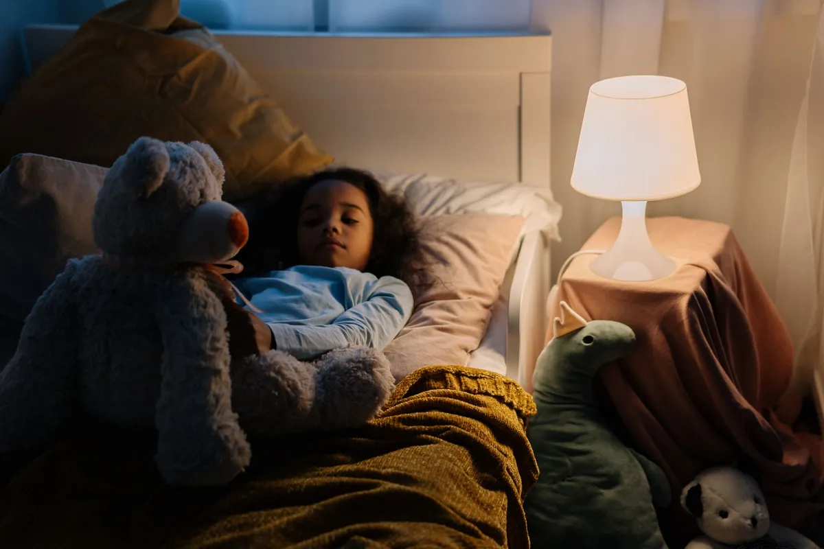 Child sleeping in bed with a stuffed animal, illustrating peaceful sleep at night.