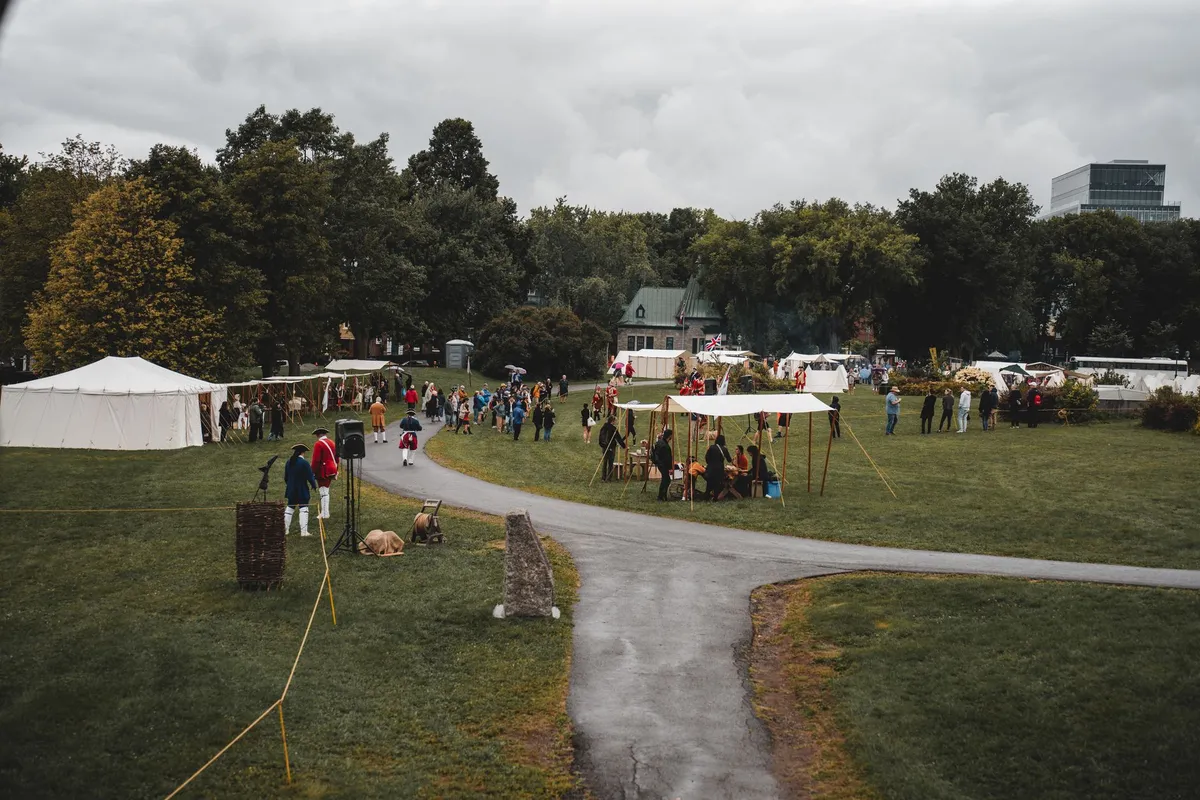 People attending a community resource fair with tents and activities in a park.
