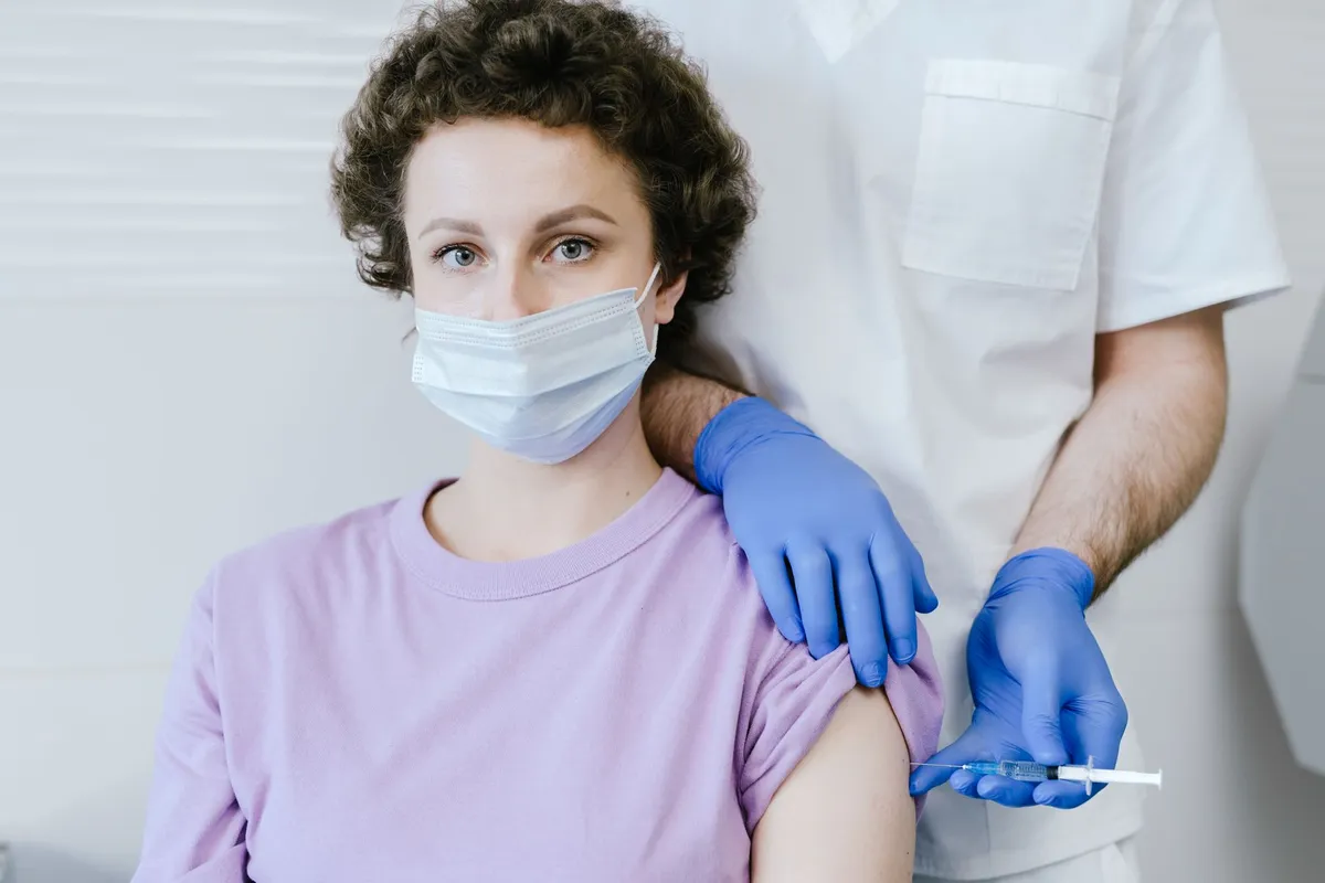 A healthcare worker administering a vaccine to a woman in a clinical setting.