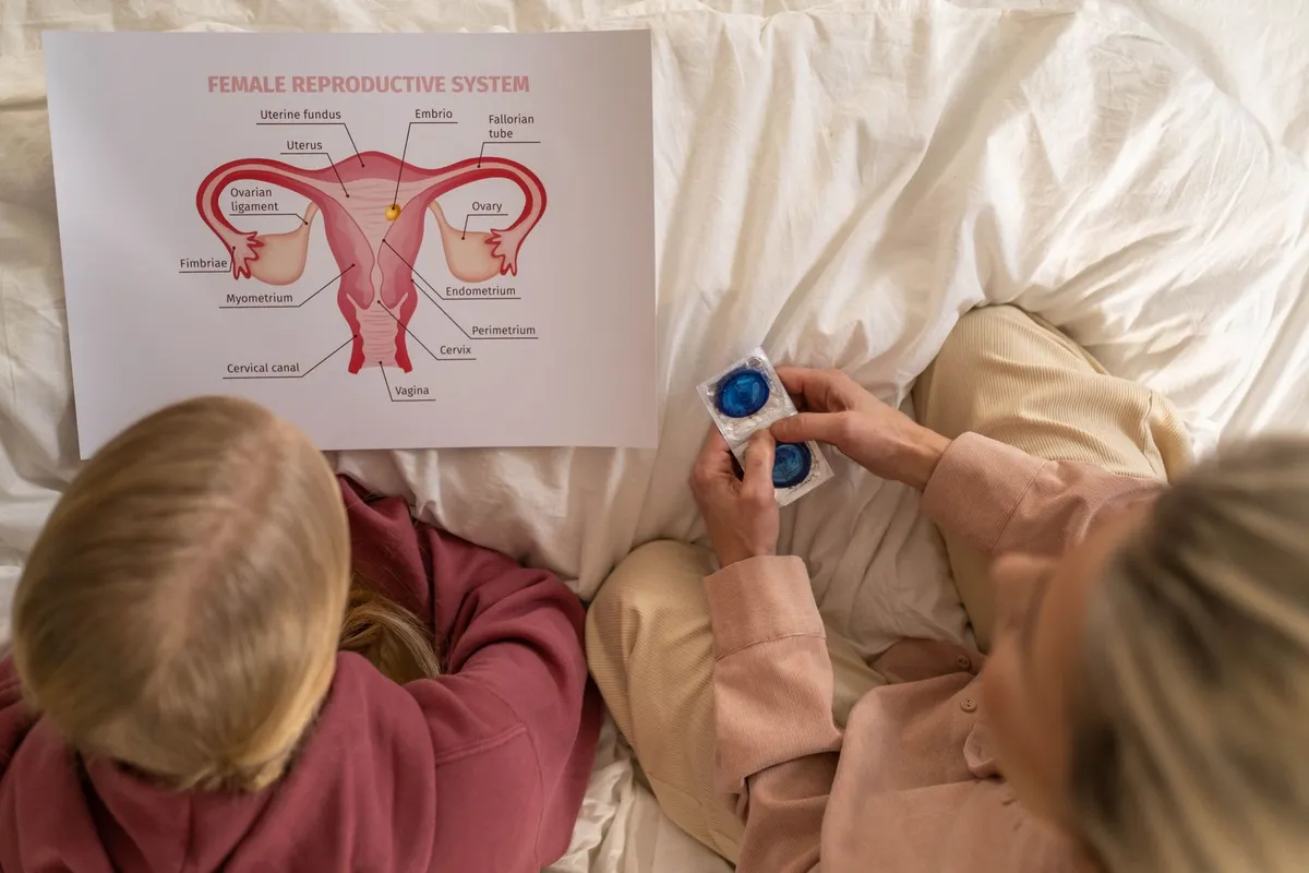 Two people examining a diagram of the female reproductive system on a bed.
