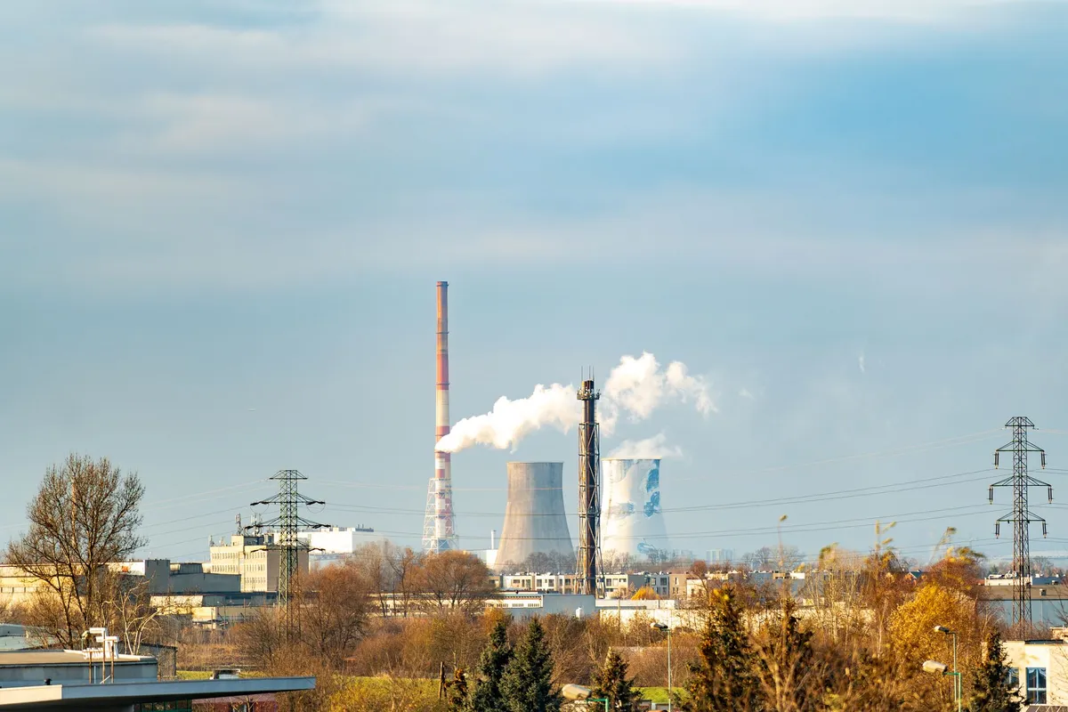 Industrial smokestacks emitting smoke against a cloudy sky