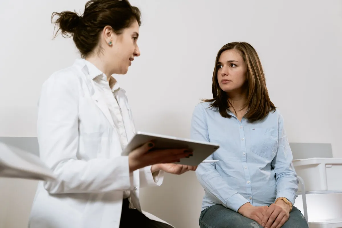 Healthcare professional discussing advice with a pregnant woman in a clinical setting.