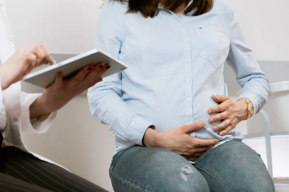 Pregnant woman holding her belly during a prenatal care appointment.