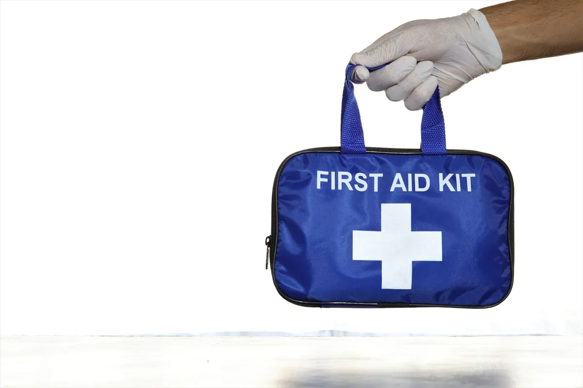 A blue first aid kit being held by a gloved hand.