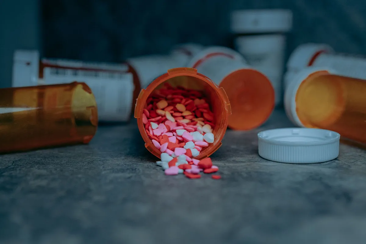 Spilled heart-shaped candies from a prescription bottle on a surface.