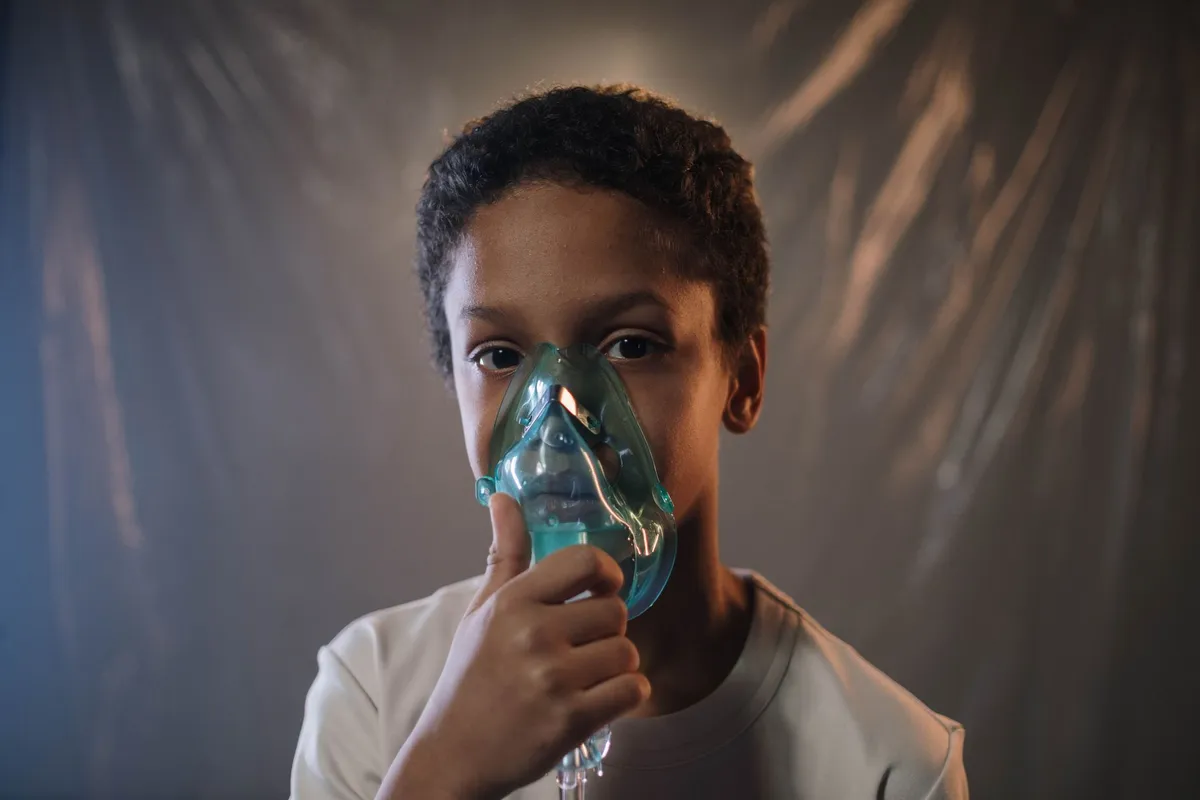 Child using a nebulizer mask for respiratory treatment in a clinical setting.