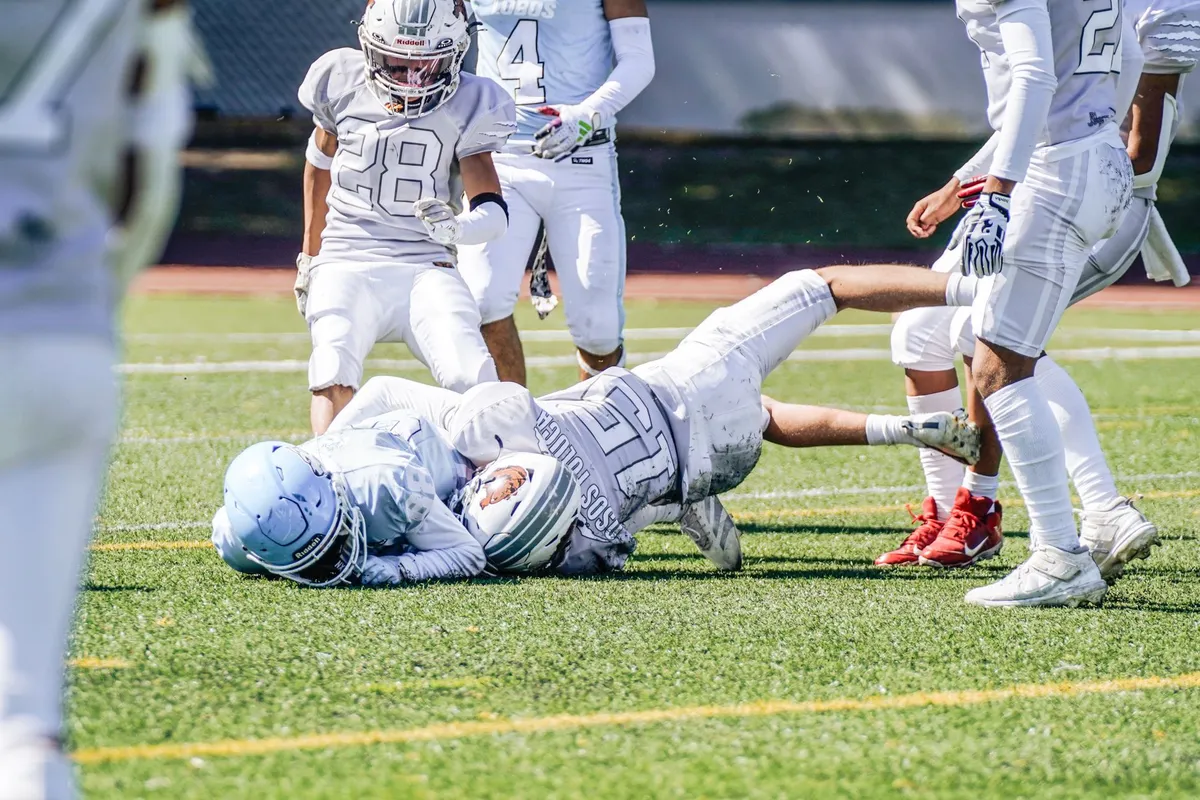 Two American football players tackling during practice on a field.