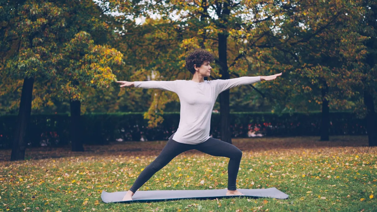 Person practicing yoga in a park surrounded by autumn foliage.