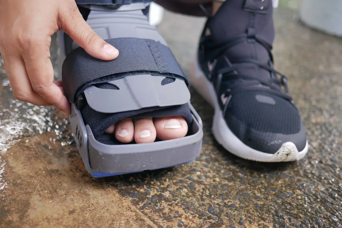 Close-up of an ankle brace being adjusted on a foot.