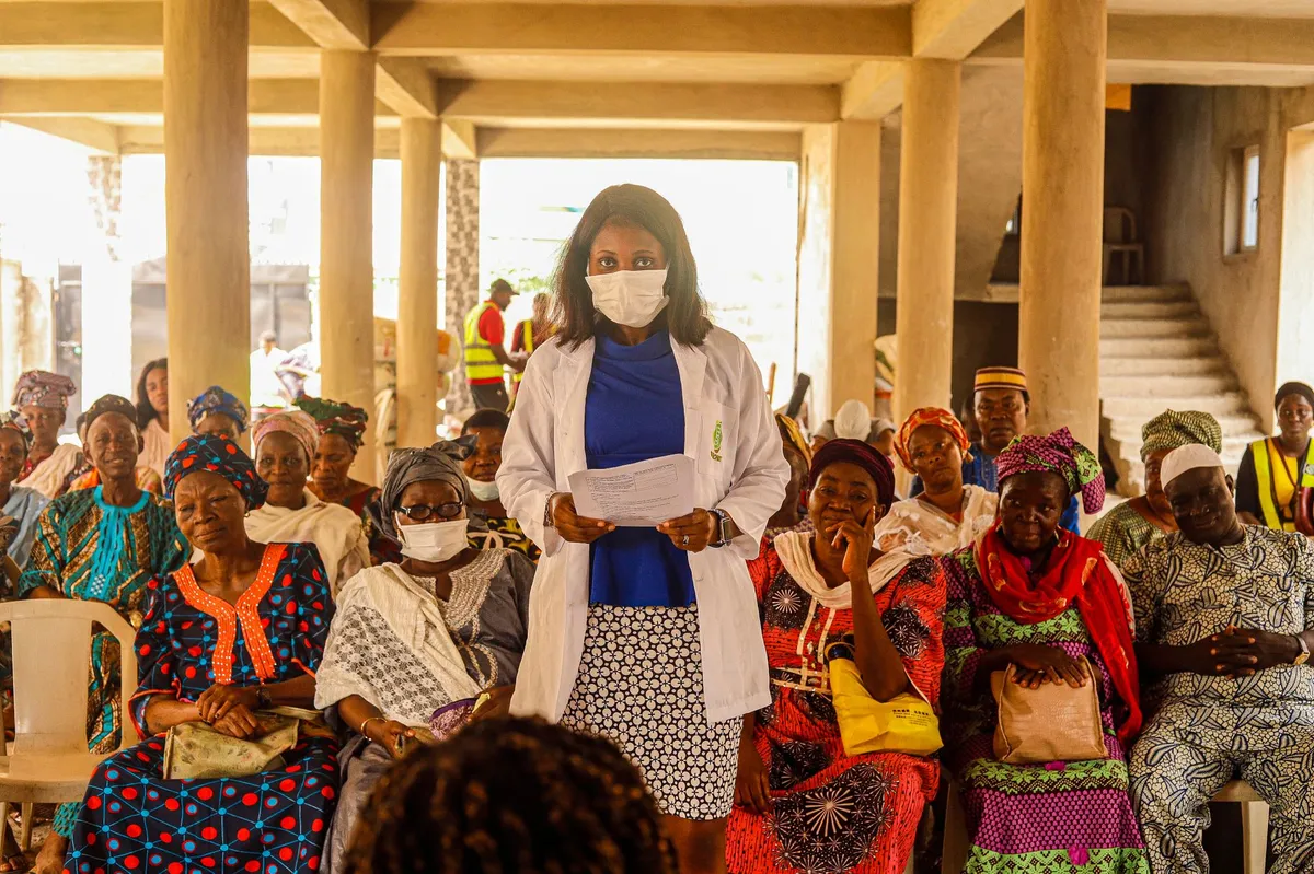 Public health worker speaking to a community group in a gathering space.