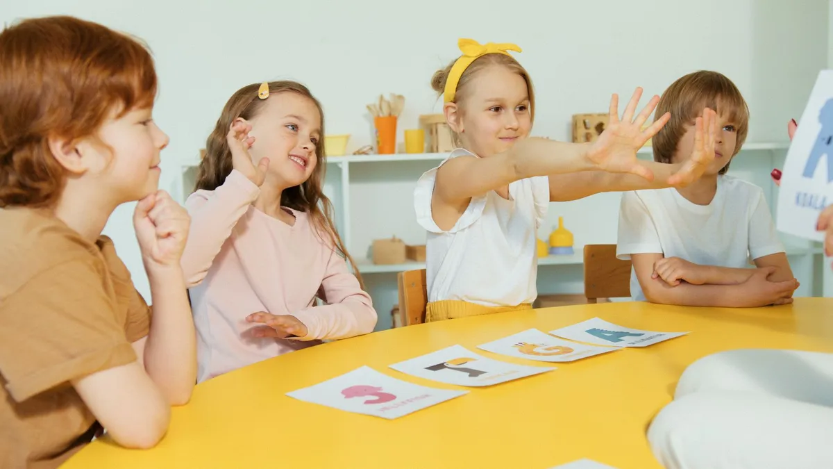 Children engaged in a group activity at a table with cards.