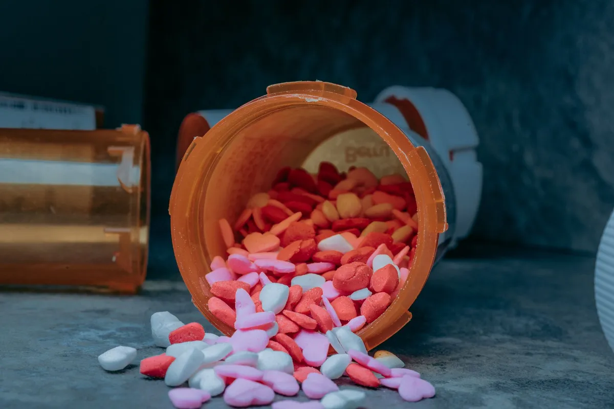Spilled prescription medication in an orange bottle on a surface.