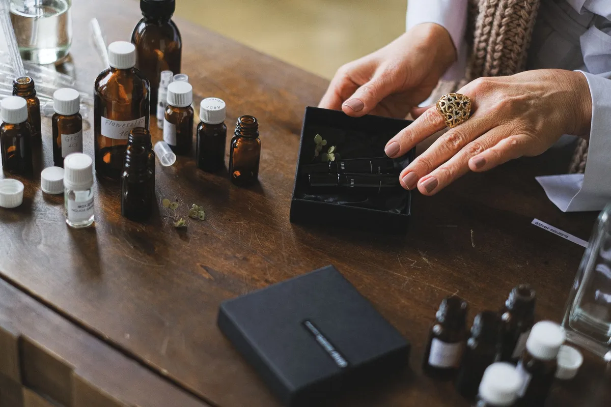 A person examining essential oils on a table with various small bottles.