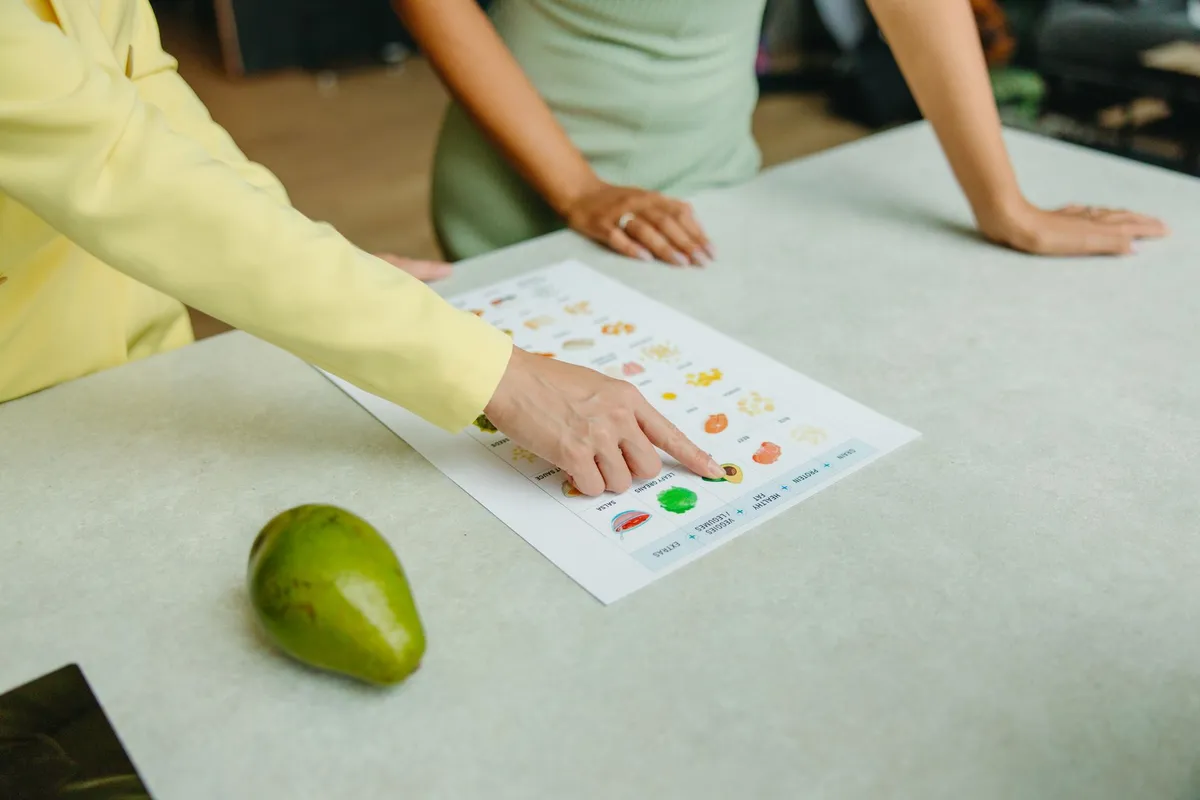 Nutritionist pointing at a diet chart with fruits and vegetables on a table.
