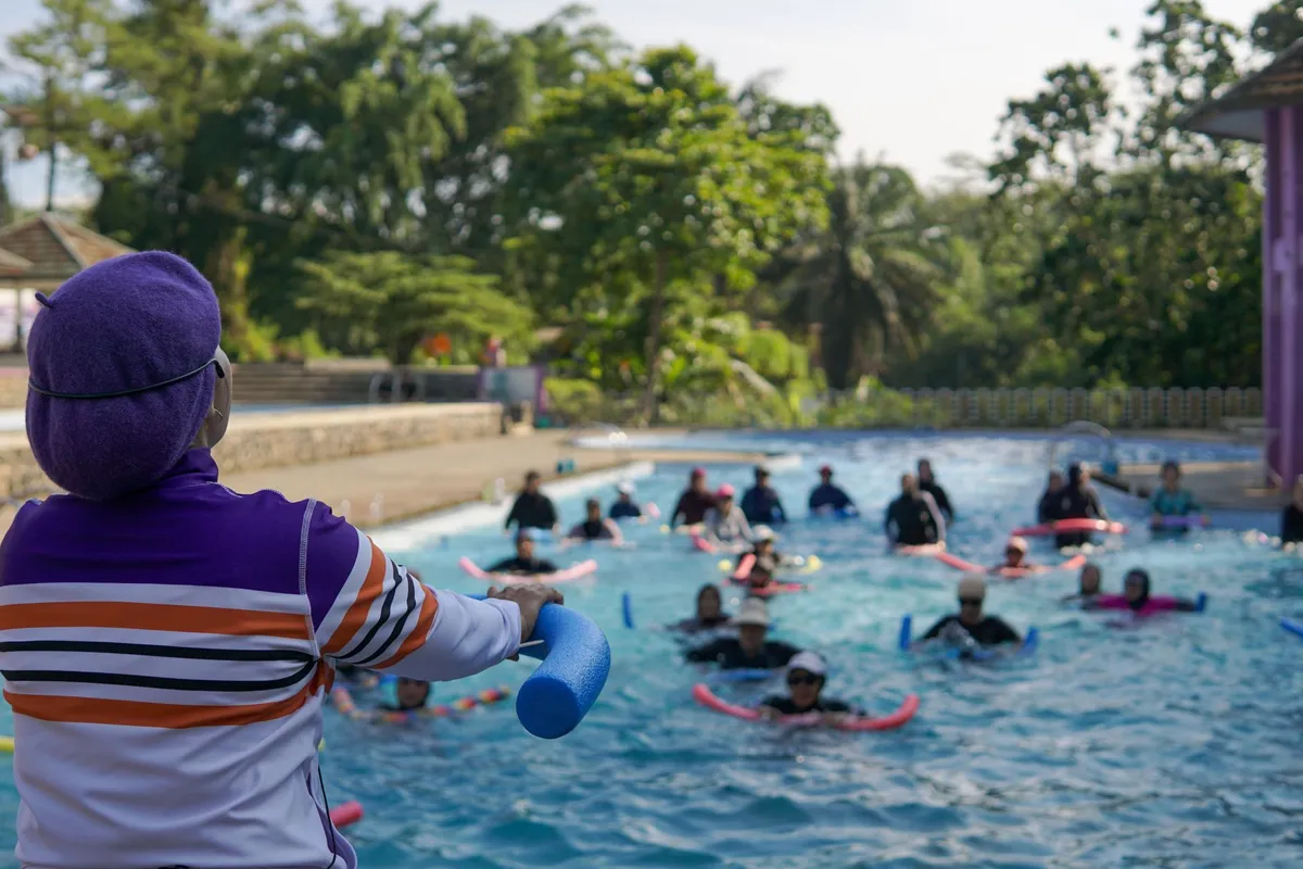 Instructor leading a warm water exercise class with participants in a pool.