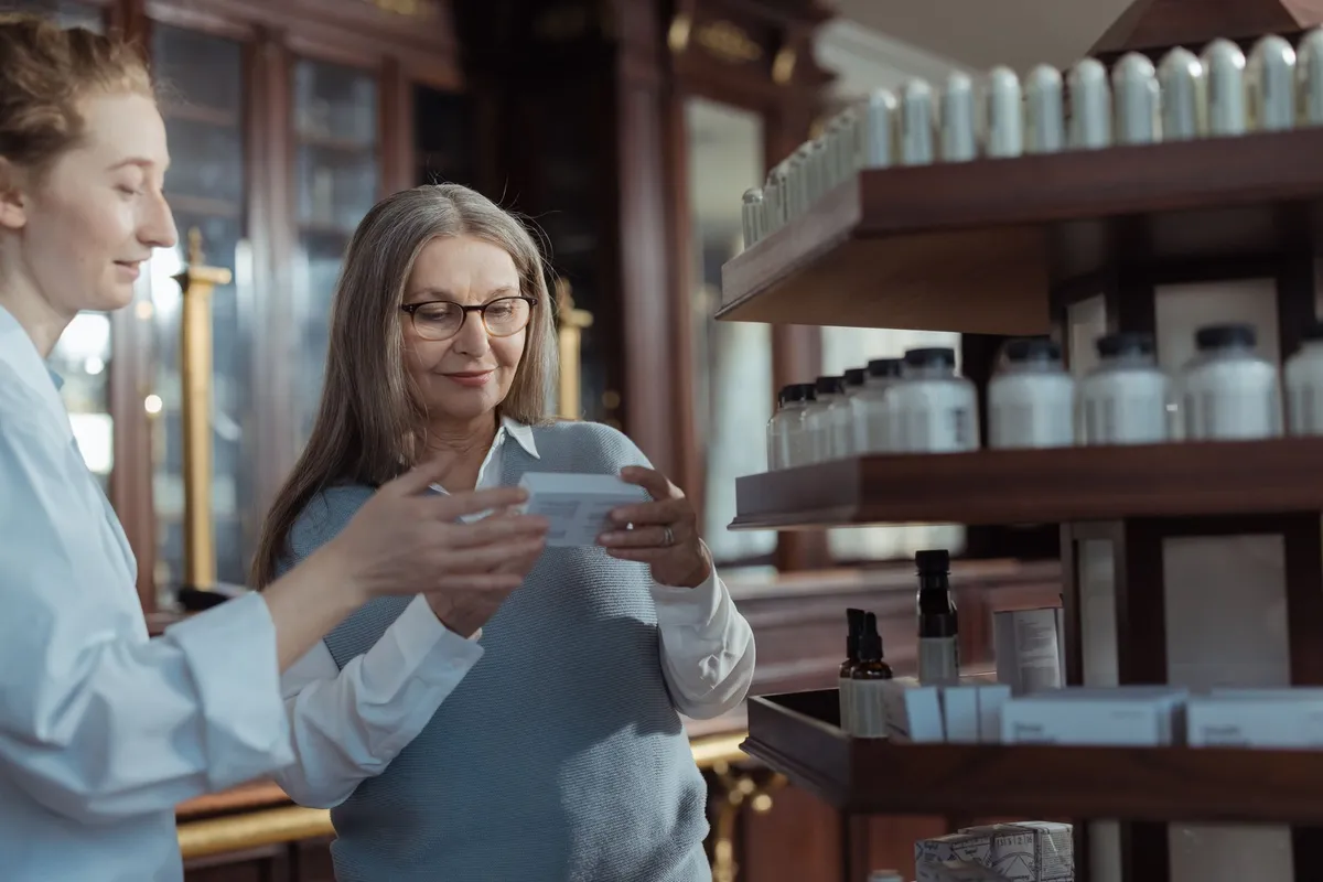 Senior woman discussing medication options with a pharmacist in a pharmacy setting.