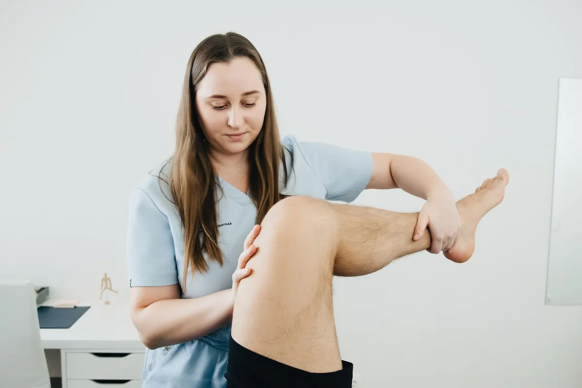 Healthcare professional examining a patient’s knee joint in a clinical setting.