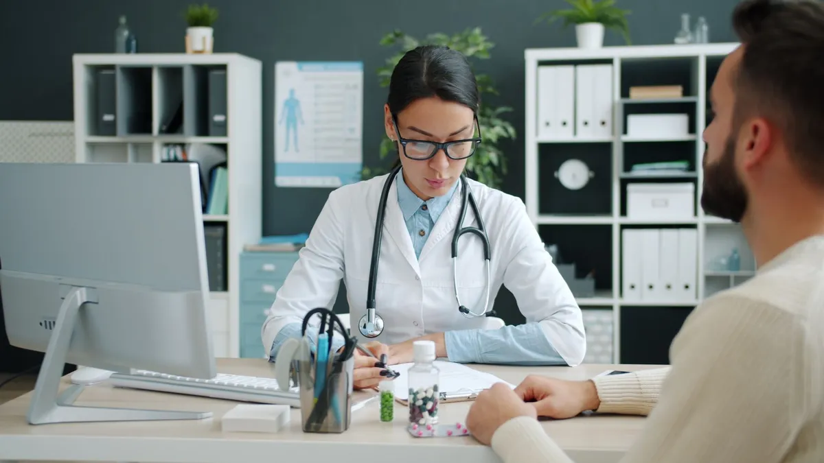 Healthcare professional discussing substance use with a patient at a desk.