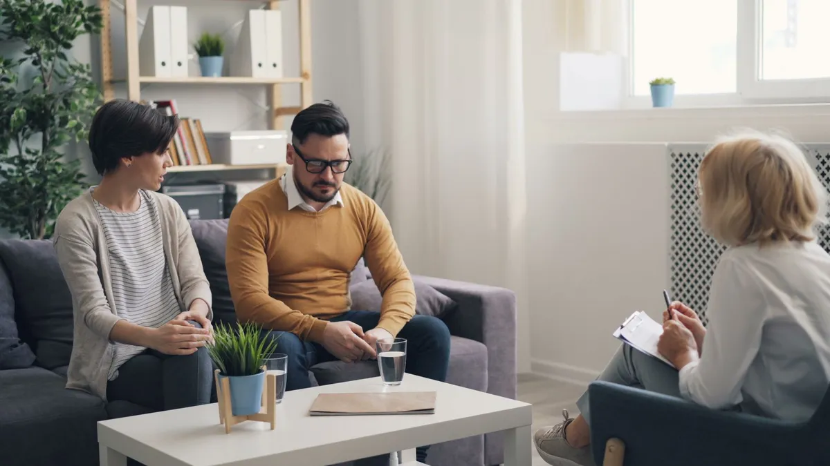 Therapist conducting a session with a couple in a cozy office setting.