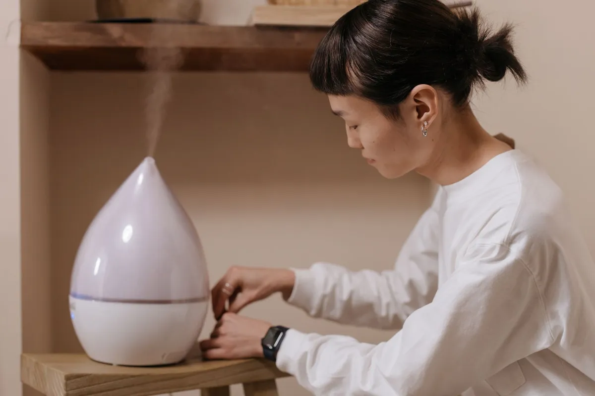Person adjusting an air purifier in a home setting.