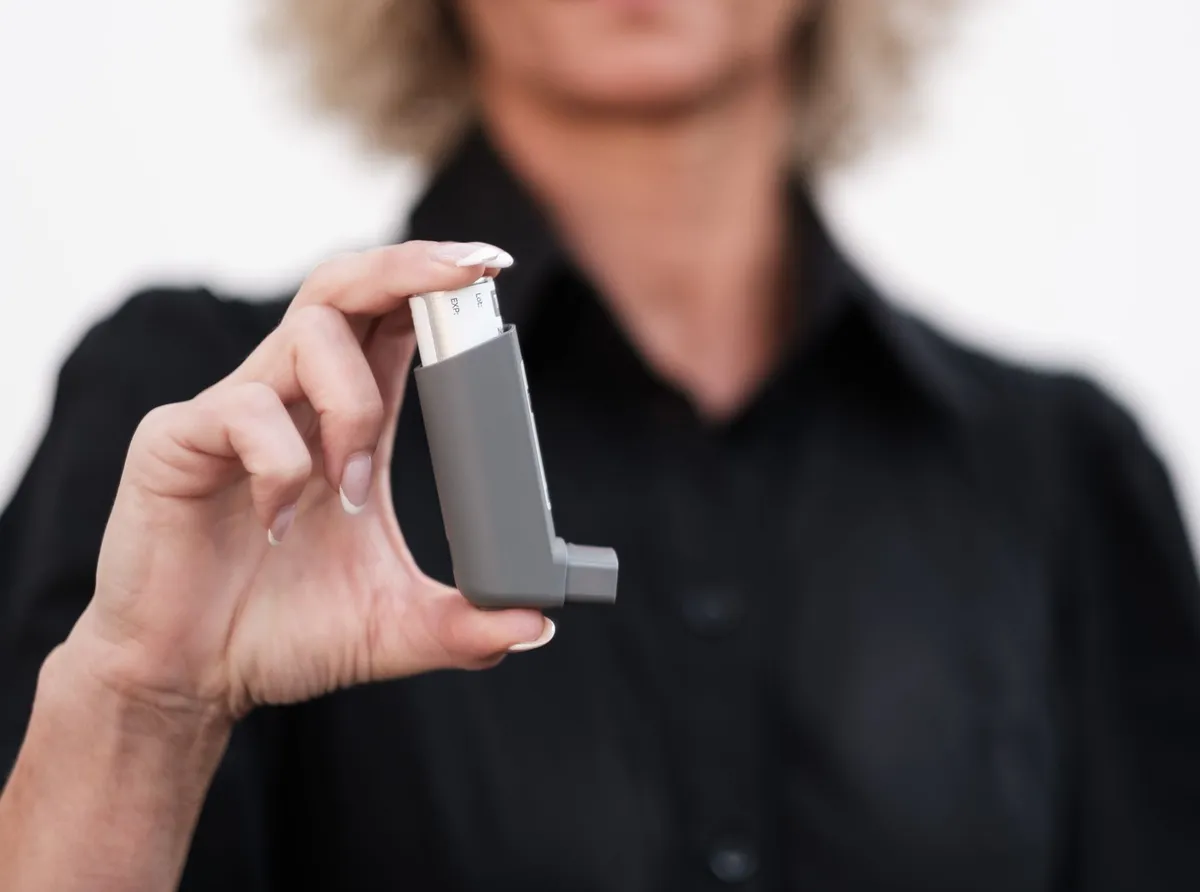 A person holding an asthma inhaler, emphasizing asthma management.