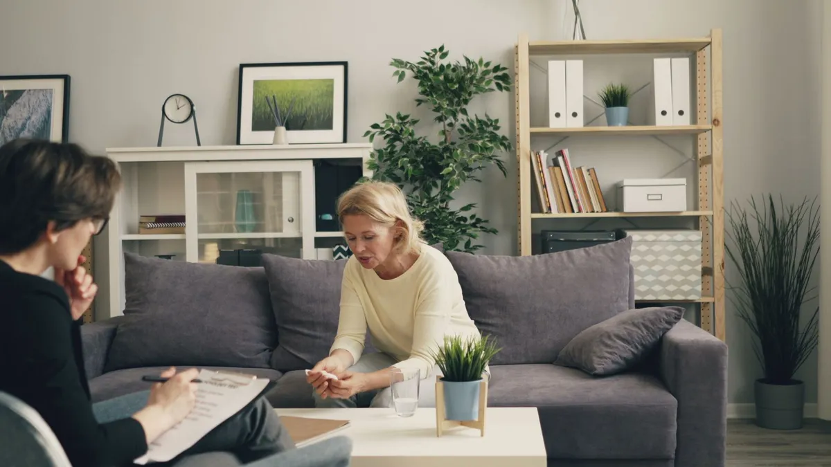 A therapist and a woman sitting on a couch during a counseling session.