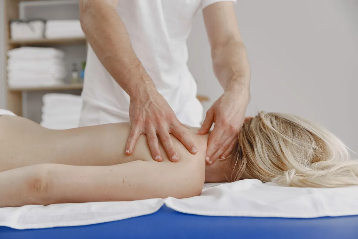 A woman receiving a massage therapy session in a clinical setting.