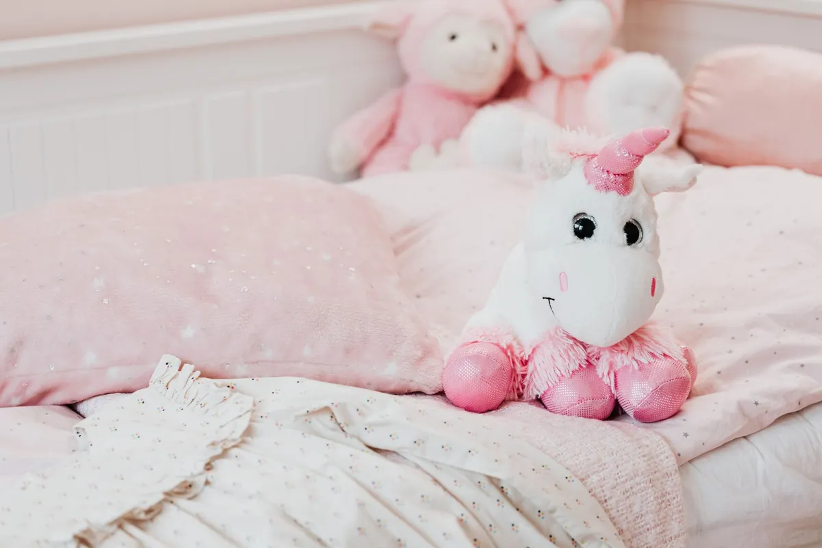 Cozy children’s bed with pink bedding and a unicorn plush toy.