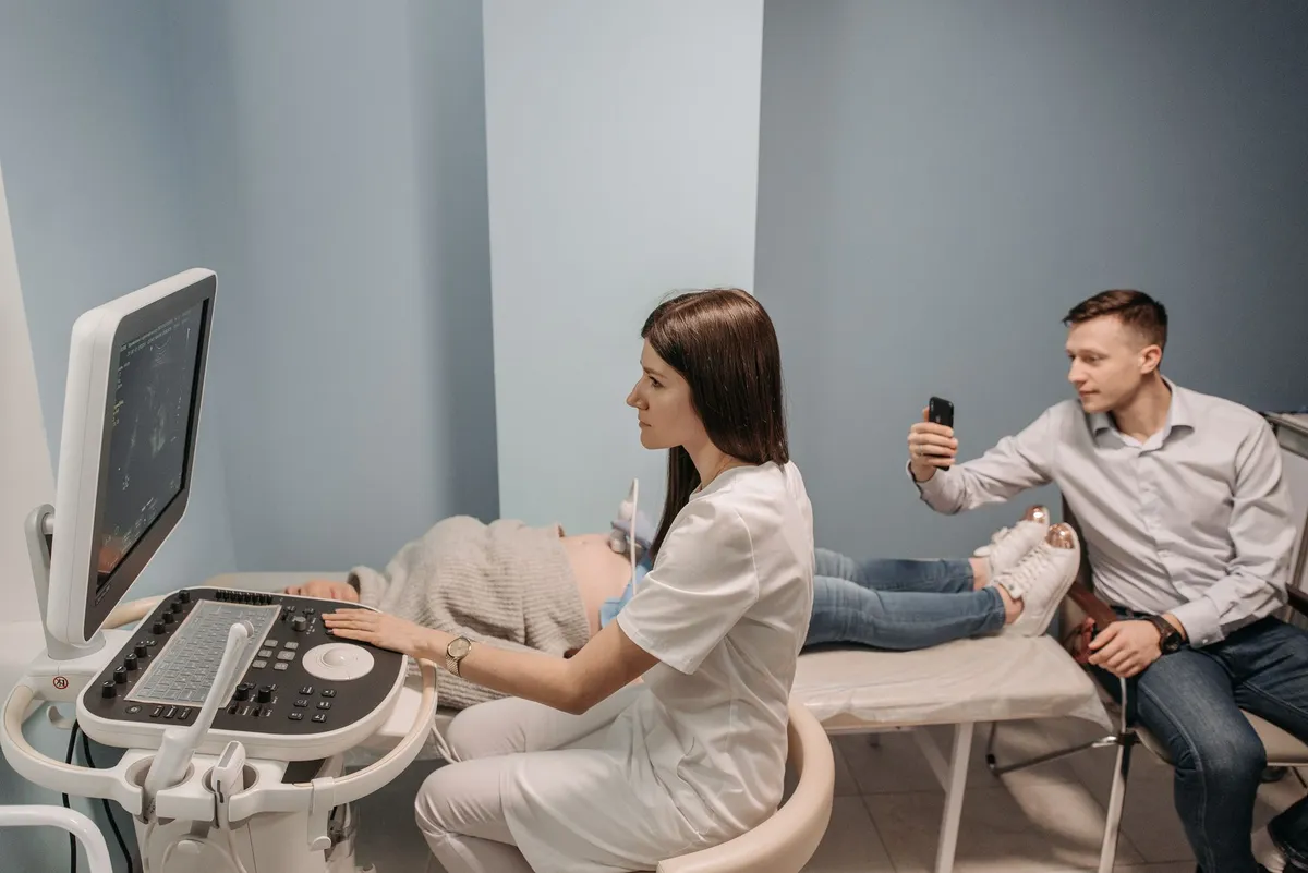 Ultrasound technician performing a scan on a pregnant woman in a clinical setting.