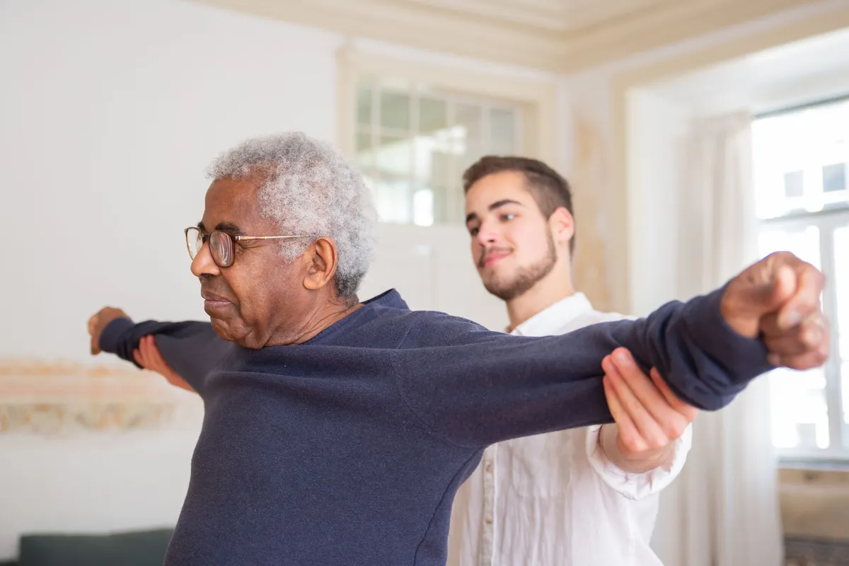 Senior man performing back exercises with assistance from a physical therapist.