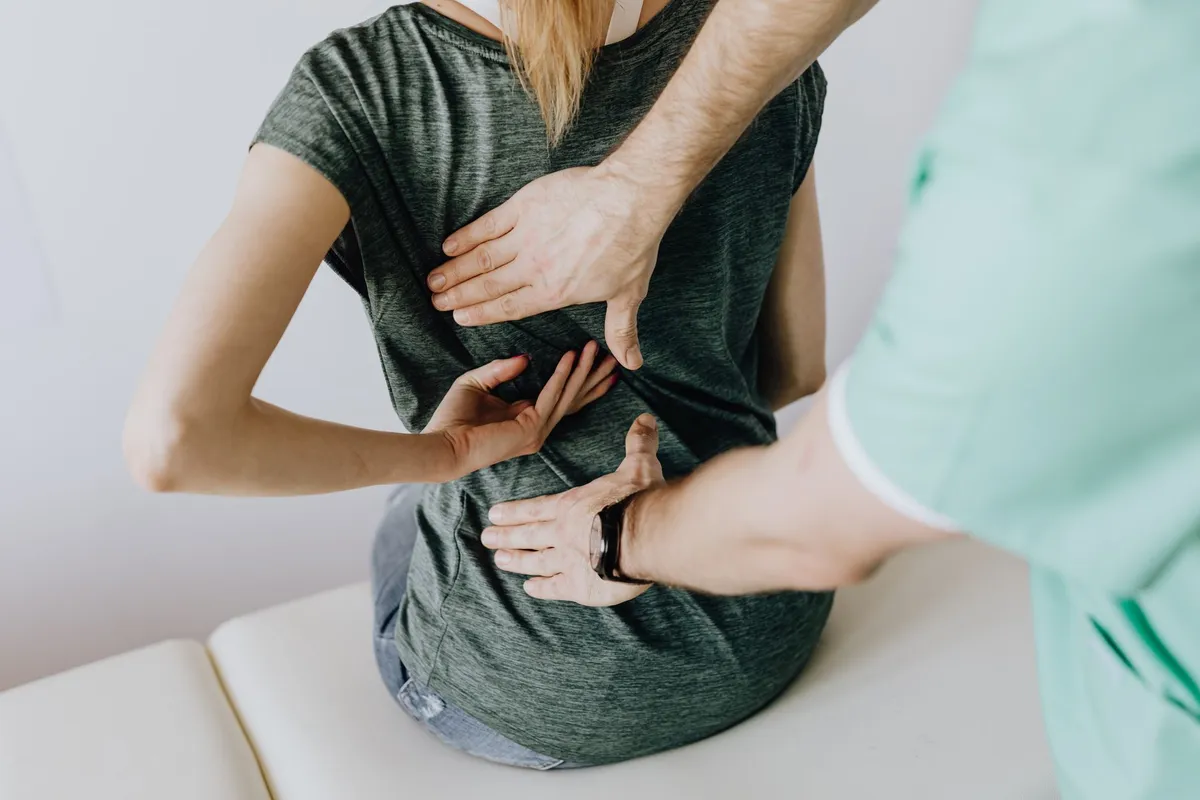 Physical therapist assisting a patient with lower back pain during an evaluation.