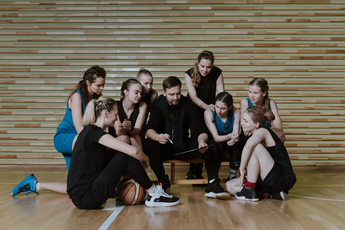 Coach instructing a basketball team during a strategy session on the court.
