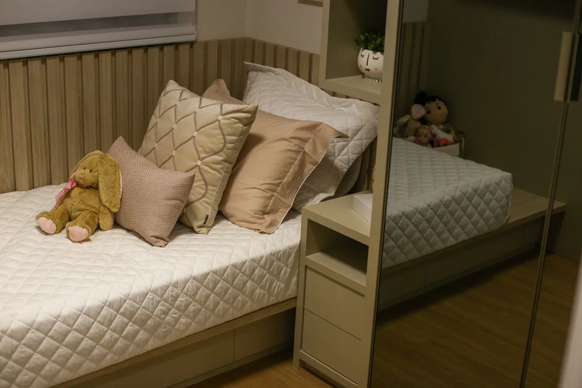 Child’s bed with pillows and stuffed animals in a cozy bedroom setting.