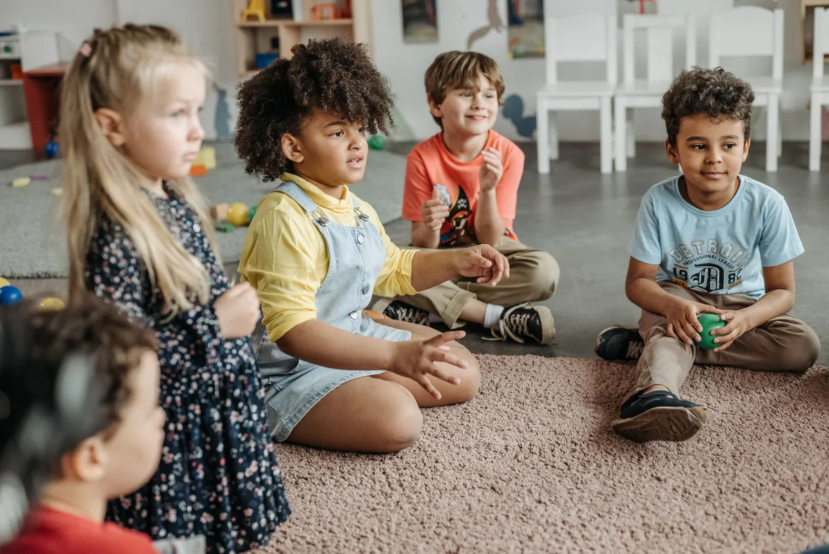 Children sitting in a circle, engaged in a group activity in a classroom setting.
