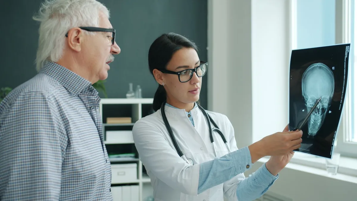 Healthcare professional explaining an X-ray of the skull to an elderly patient.