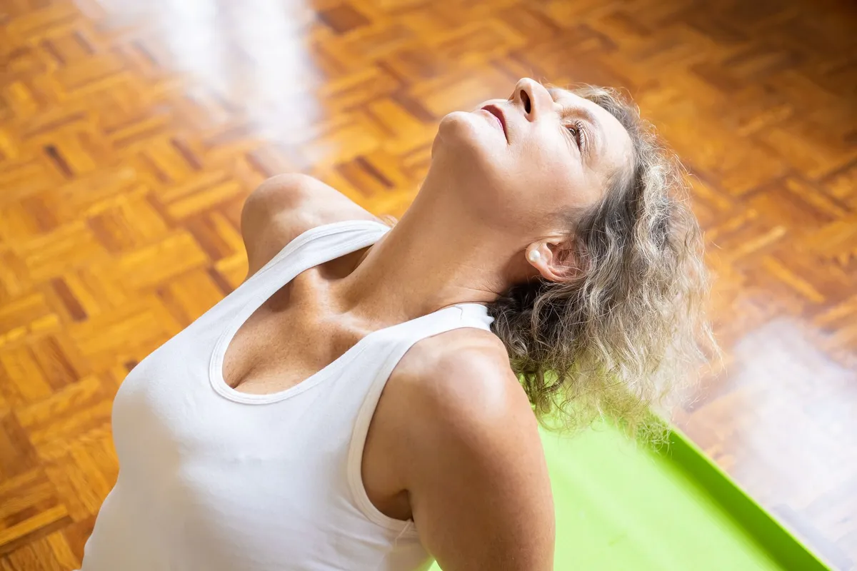 Woman performing neck exercises to relieve vertigo symptoms indoors.