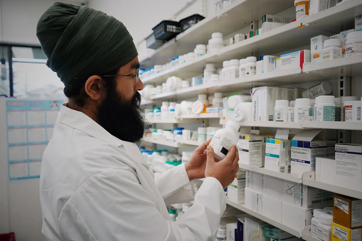 Pharmacist examining prescription bottles on a shelf in a pharmacy.