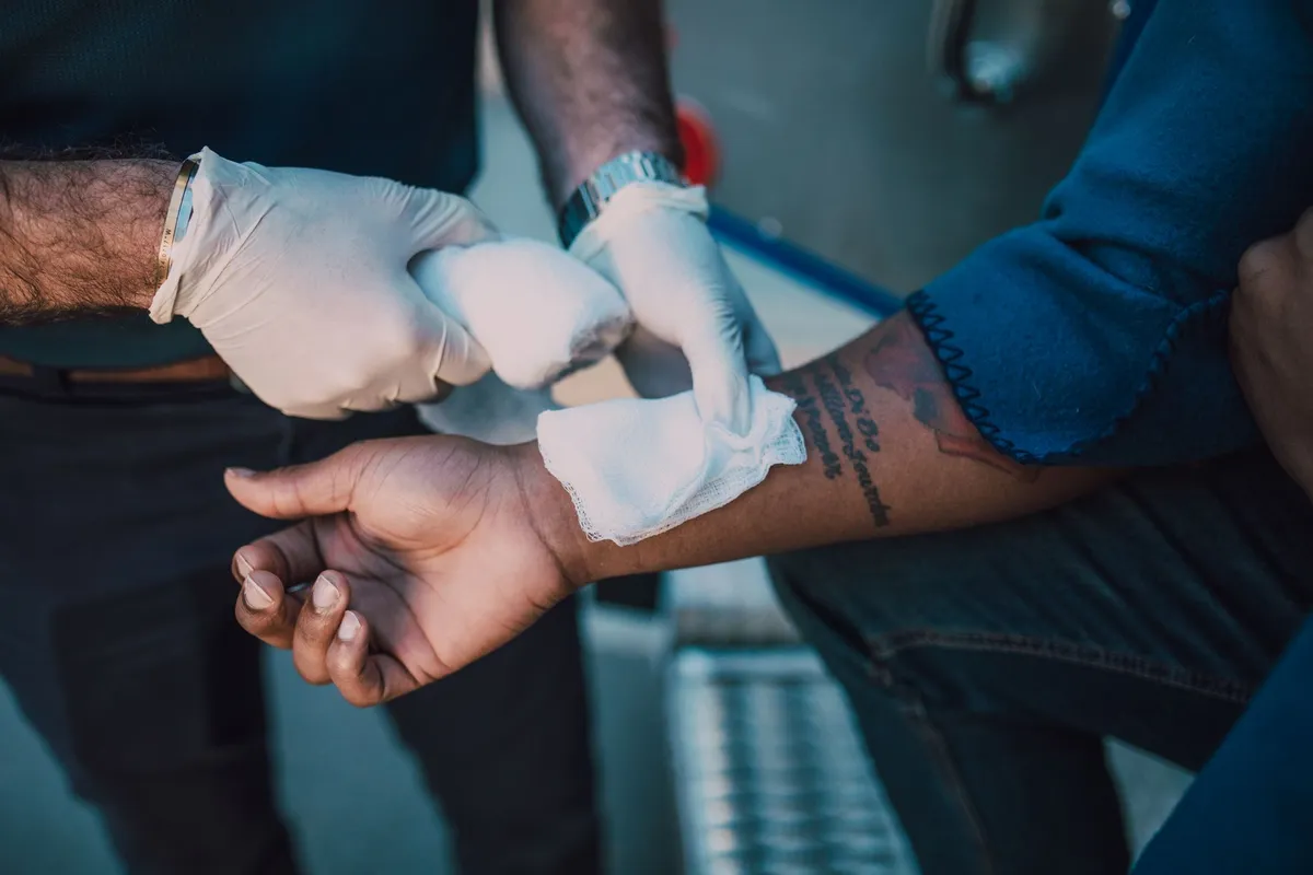 Applying a bandage to a bleeding wound on an arm.