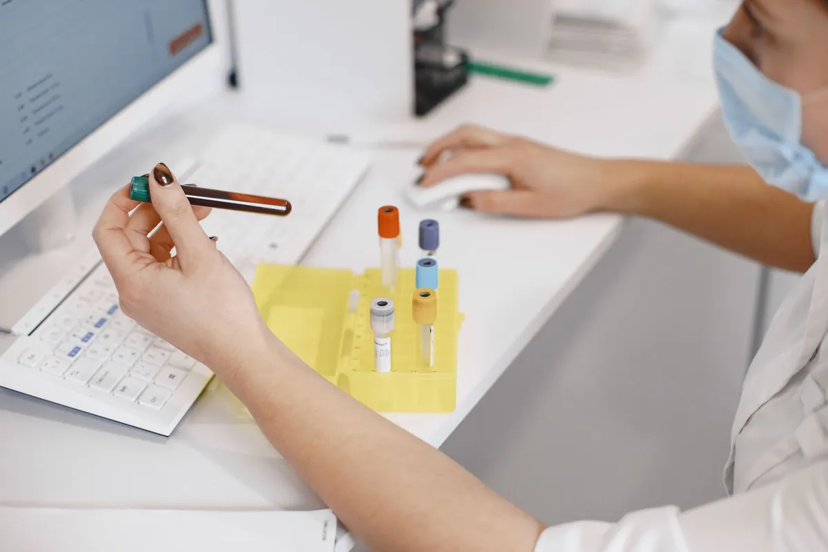 Laboratory technician analyzing blood samples at a computer station.