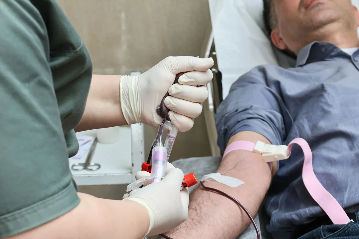 Nurse drawing blood from a donor’s arm during a donation process.
