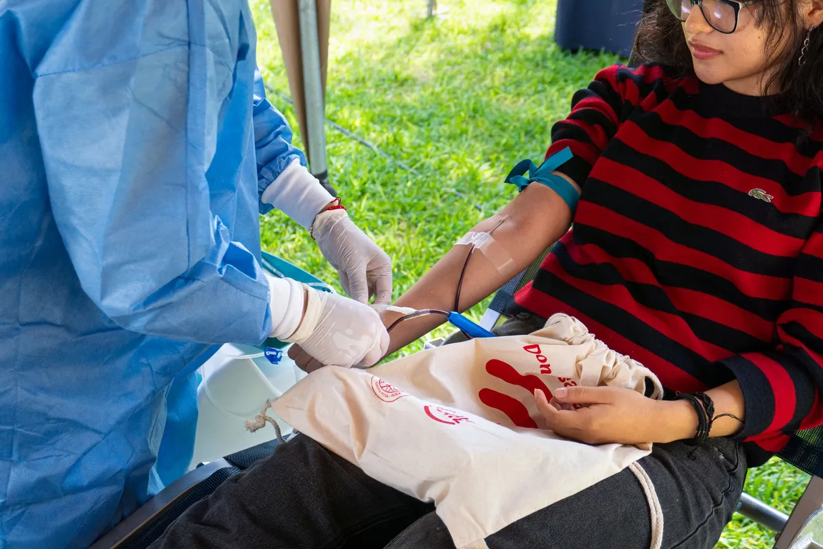 Person donating blood at a donation center with medical staff present.