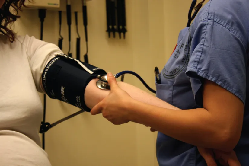 Nurse measuring a patient’s blood pressure with a sphygmomanometer.