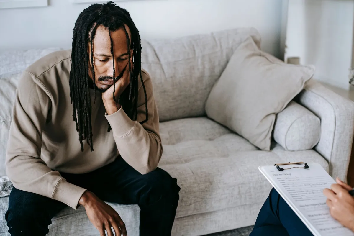 Man sitting on a couch looking worried during a therapy session.