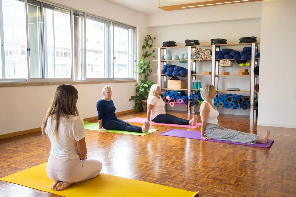 Older women practicing yoga in a bright studio with mats and props.