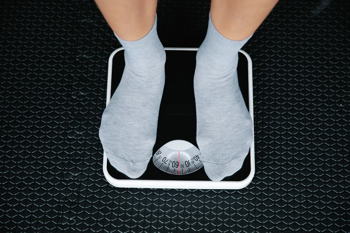 Person standing on a scale measuring weight in socks.